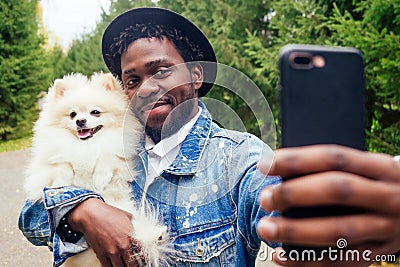 African american man making self portrait with fluffy spitz in summer spring park Stock Photo