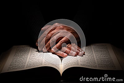 African American Man Praying with Hands on Top of the Bible Stock Photo