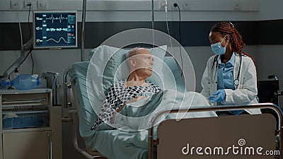 African american medic talking to sick patient in hospital ward Stock Photo