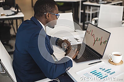 African American men in a business suit are working on a laptop studying stock market charts and technical analysis. Stock Photo