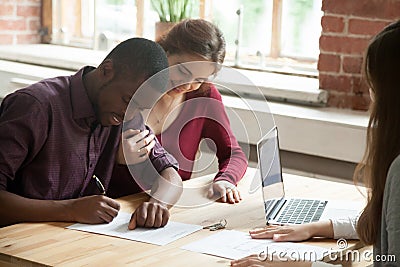 Multiethnic couple signing house purchase agreement. Stock Photo