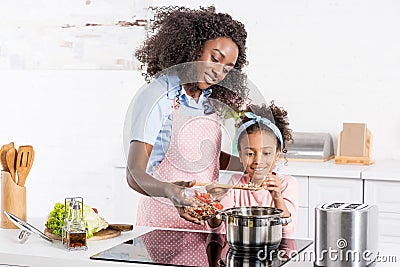 african american mom and daughter cooking on electric Stock Photo