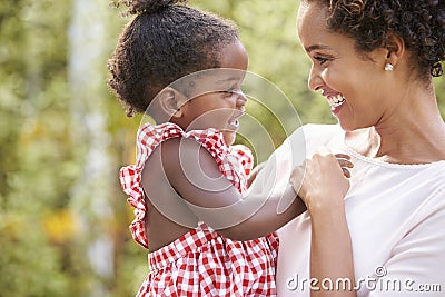 African American mother carries baby daughter and holds hand Stock Photo