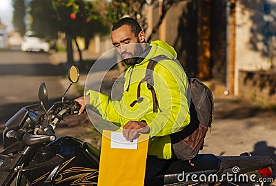 African American motorcycle courier on motorbike with envelope for delivery Stock Photo