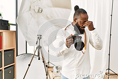 African american photographer man working at photography studio tired rubbing nose and eyes feeling fatigue and headache Stock Photo
