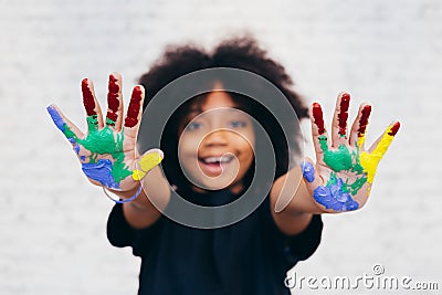 African American playful and creative kid getting hands dirty with many colors Stock Photo