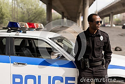 african american police officer leaning back on car Stock Photo