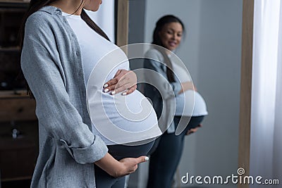 african american pregnant woman looking at her belly Stock Photo