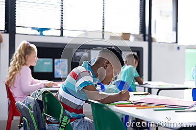African american schoolboy working at his desk in diverse elementary class, copy space Stock Photo