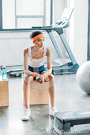 african american sportswoman in headband and headbands resting on wooden box Stock Photo