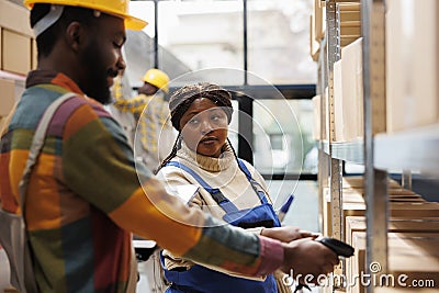 African american storehouse manager looking at worker scanning parcels Stock Photo