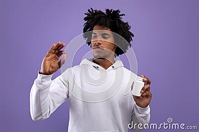 African American teenager holding jar and pill over violet studio background. Health care, treatment of coronavirus Stock Photo