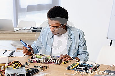 african american teenager soldering computer circuit with soldering iron Stock Photo