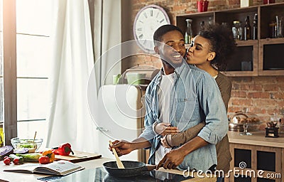 African-american wife kissing husband in kitchen Stock Photo