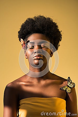 African american woman with butterflies with closed eyes isolated on brown Stock Photo