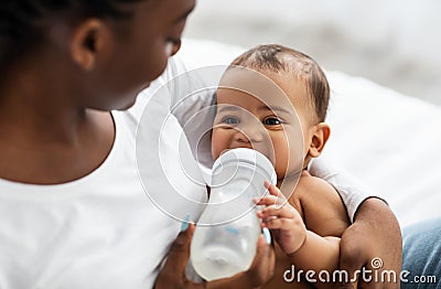 African American woman feeding her child from baby bottle Stock Photo