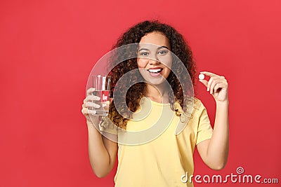 African-American woman with glass of water and vitamin pill on background Stock Photo