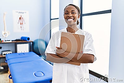African american woman physiotherapist smiling confident holding medical report at rehab clinic Stock Photo