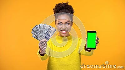 African-American woman showing smartphone and bunch of dollars, money transfer Stock Photo