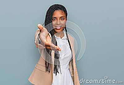 African american woman wearing business jacket smiling friendly offering handshake as greeting and welcoming Stock Photo