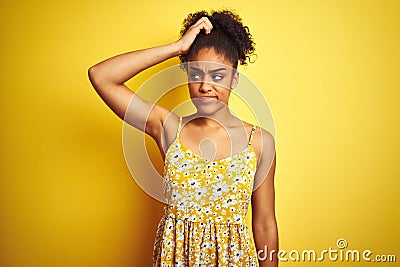 African american woman wearing casual floral dress standing over isolated yellow background confuse and wondering about question Stock Photo