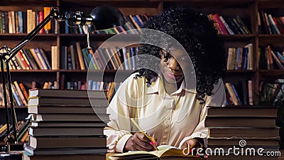 African-American woman writes in notebook in public library Stock Photo