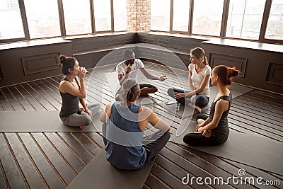 African-american yoga instructor talking to diverse group sittin Stock Photo