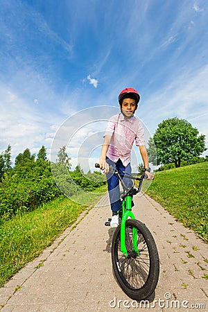 African boy in red helmet rides bright green bike Stock Photo