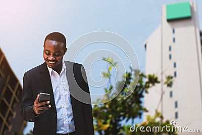 African businessman wears a black suit and uses a stylish smartphone with smile and happy Stock Photo