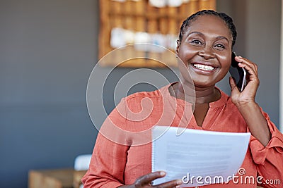 African businesswoman using a cellphone and reading documents at work Stock Photo