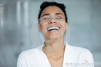 African cheerful woman in white bathrobe laughing standing in bathroom Stock Photo