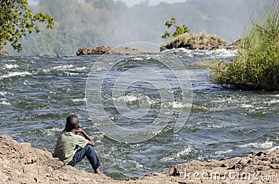 African Child setting on Zambezi river side on top of Victoria falls , Livingstone , Zambia Editorial Stock Photo