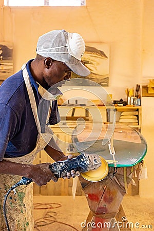 An African Craftsman surfboard Shaper working in a repair workshop Editorial Stock Photo
