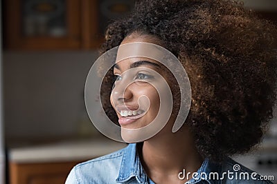 African curly-haired teenage girl smiling staring into distance Stock Photo