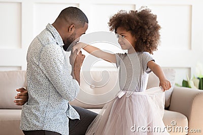 African dad standing on knee kissing hand of kid daughter Stock Photo