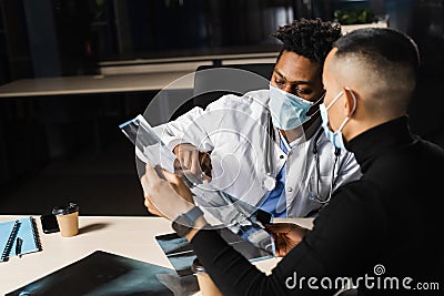 African doctor show x-ray asian patient. Pneumonia and pleurisy. Black surgeon analyzing x ray and diagnosis patient in Stock Photo