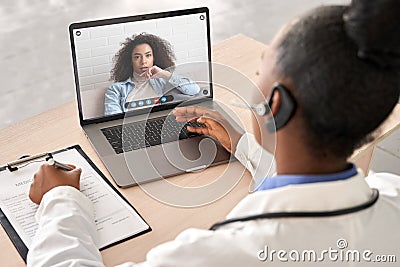 African doctor talk to patient by online webcam video call on laptop screen. Stock Photo