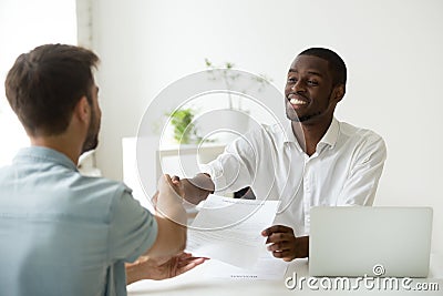 African employer handshaking new hire caucasian employee holding Stock Photo