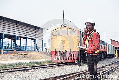 African engineer control a the train on railway with talking by radio communication or walkie talkie Stock Photo