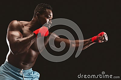 Side view of black fighter making punch over black background Stock Photo