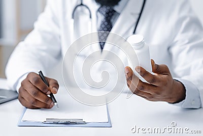 African general practitioner holding pills box and writing Stock Photo