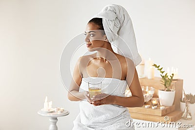 African girl with towel on head holding glass smiling looking in side resting in spa resort. Stock Photo