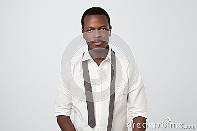 african guy in white shirt standing untied after hard working day or party. I do not know how to wear tie correctly Stock Photo