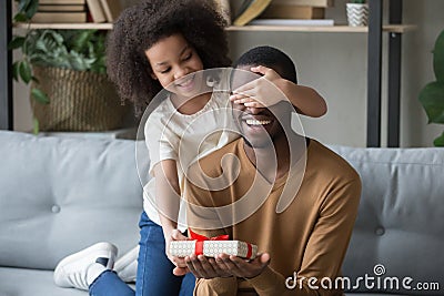 African kid daughter closing eyes congratulating dad giving gift box Stock Photo