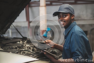 African maintenance male checking car with use wrench and tablet , service via insurance system at Auomobile repair and check up Stock Photo