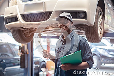 African maintenance male checking tire service via insurance system at garage Stock Photo