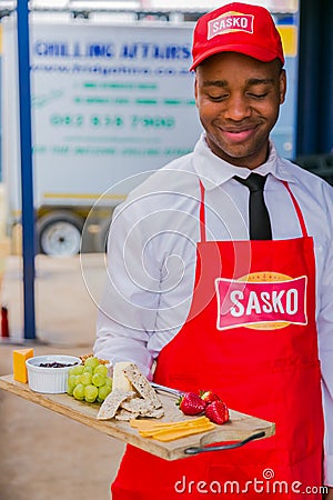 African male waiter holding a board of cheese and crackers Editorial Stock Photo