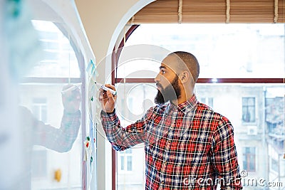 African man with beard standing and writing on whiteboard Stock Photo