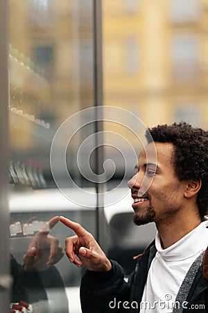 African man buys drink or sweets at vending machine outside Stock Photo