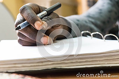 African man holding pen in hand to write on blank white paper Stock Photo